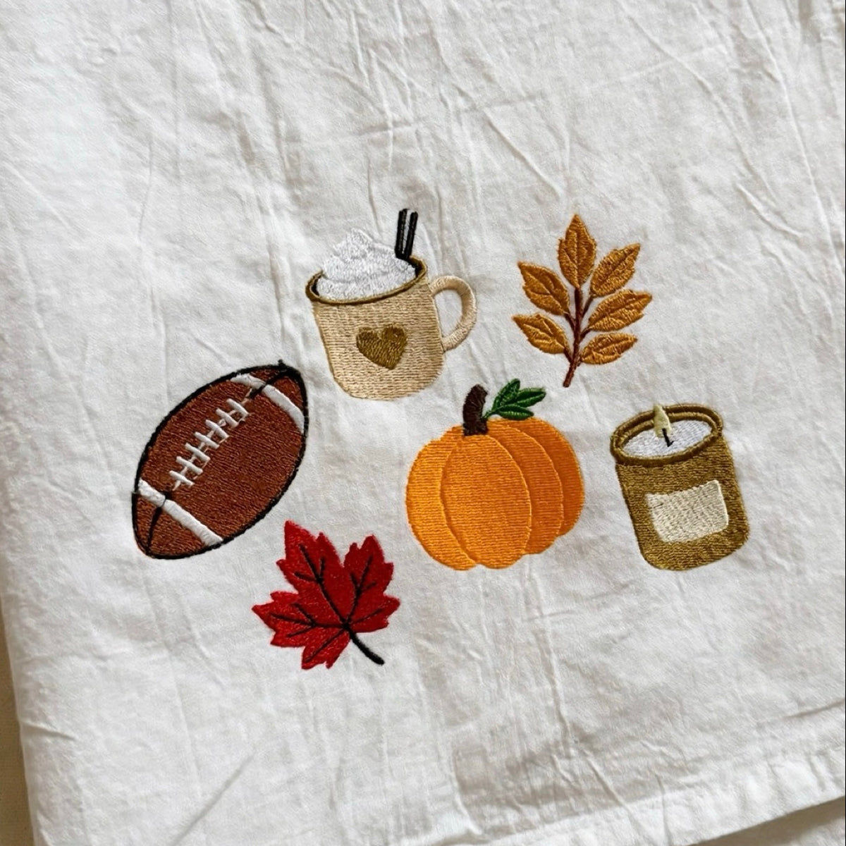 Close-up of embroidered autumn motifs on the white fall tea towel