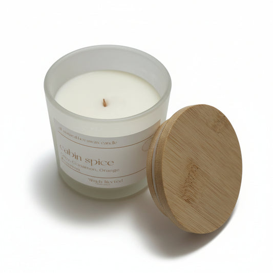 Candle in a glass jar with a wooden lid on a white background