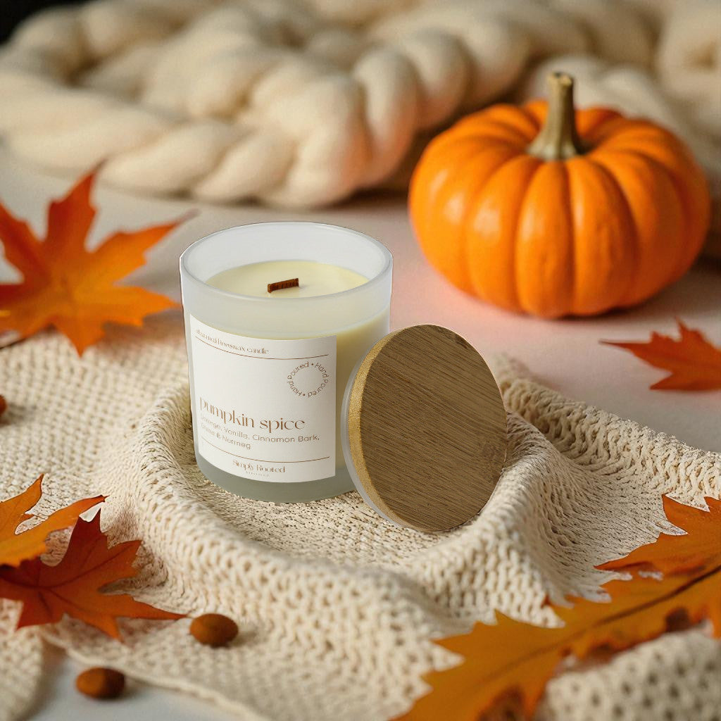 Pumpkin spice candle with wooden lid on a textured surface with pumpkins and leaves